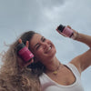 mujer sosteniendo un myoflow y un ciclocalm, sonriendo sobre fondo de nubes. Luego, myoflow en un vaso curvo de vidrio sobre fondo rosa plano . Luego, cclocalm y myo flow sobre fondo planorosa. Finalmente, mujer jobven con productos. 